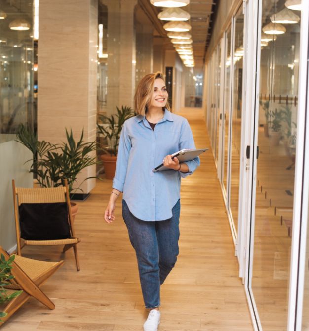 Person walking in a hallway with computer